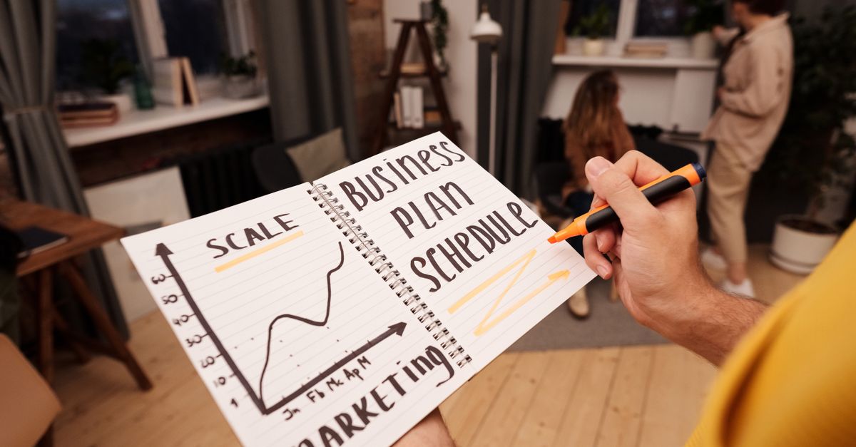 Person holding a notebook with planning details and a business graph.